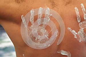 Bare man back hand marked sunscreen