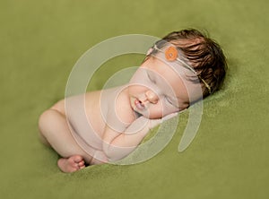 Bare newborn baby with headband