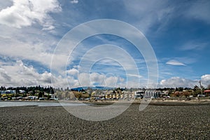 Bare rocks on Departure Bay Beach at low tide on a sunny day. View of the residences along Departure Bay Road, Nanaimo