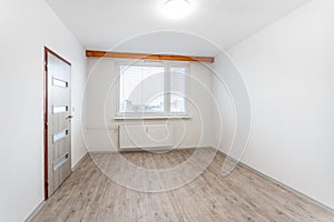 bare room with pristine white walls, a wooden laminated floor, and a large window that allows natural light to flood in