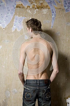 Bare teen boy standing at wall
