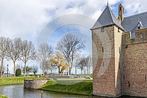 Bare trees, moat, green grass, Radboud castle tower with brick walls and canons in the background
