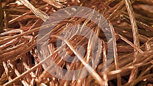 Bare wires of copper cables are lying in a heap of scrap metal in factory premise, close-up shot