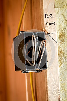Close up of a black plastic electrical box mounted to the wall with wires exposed