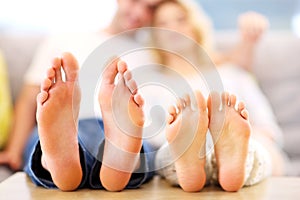 Barefeet of a happy couple lying on a sofa