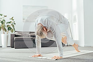 barefoot adult man doing lunge yoga exercise on mat