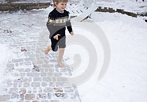 Barefoot boy of 4-5 years old runs joyfully in the snow