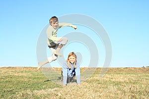 Barefoot boy jumping over girl