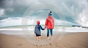 Barefoot boy with mother come into the sea