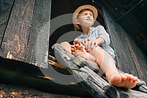 Barefoot boy sits on ladder in barn attic