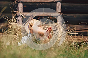 Barefoot boy sleeps on the grass near ladder in haystack photo