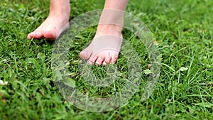 barefoot child girl walking on a green grass outdoor closeup
