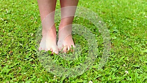 barefoot child girl walking on a green grass outdoor after the rain