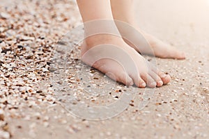 Barefoot child legs on sand