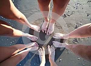 Barefoot feet of a family of five with legs on the sandy beach f