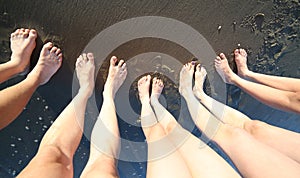 Barefoot feet of a young family of five with long legs on the se