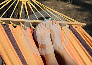 barefoot feet of a young girl while resting in the hammock in th