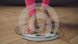 Barefoot female legs standing on weighing scale