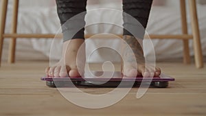 Barefoot female legs stepping on weighing scale