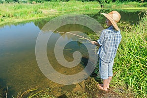 Barefoot fishing boy angling in transparent