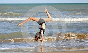Barefoot girl in black swimsuit from rhythmic gymnastics exercises on the seashore