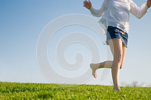 Barefoot girl runs on a green lawn