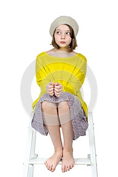 Barefoot girl sitting on a stepladder with a mysterious look.