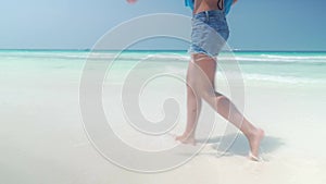 Barefoot girl walks on sandy beach along ocean