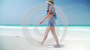 Barefoot girl walks on sandy beach along ocean