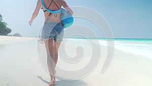 Barefoot girl walks on sandy beach along ocean