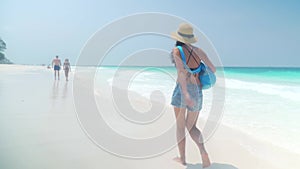 Barefoot girl walks on sandy beach along ocean