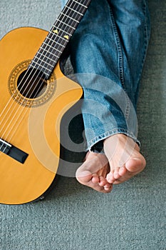 Barefoot Guitarist With Legs Outstretch Beside Guitar