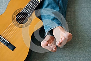 Barefoot Guitarist With Legs Outstretch Beside Guitar