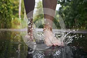 Barefoot leg of young man stepping to puddle