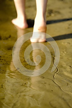 Barefoot legs on beach sand
