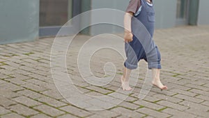 barefoot legs toddler baby boy walking on pavement grey stone path. first steps