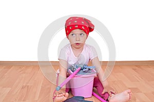 Barefoot little girl with mop and bucket sitting on the floor isolated