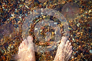 Barefoot male feet on the beach with pebbles