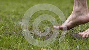 Barefoot man jumps in water in grass