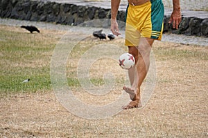 Barefoot man kicks soccer ball on grassy field