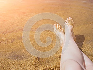 Barefoot not tanned female legs on the sandy shore of the lake