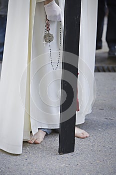Barefoot penitent doing penance with a wood cross in a Holy week procession photo