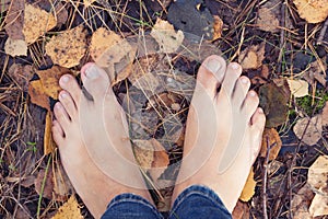 Barefoot person standing on the ground in autumn forest photo