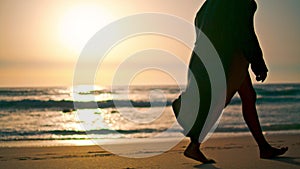 Barefoot girl walking beach sand at summer sunrise. Woman stepping seashore.