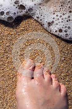 Barefoot on the sand and sea foam