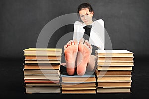 Soles of bare feet of teenage girl on top of old books photo