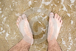 Barefoot in sea with foam
