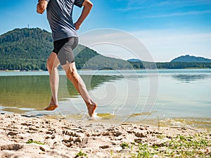 Barefoot sportsman run in water along the sandy beach