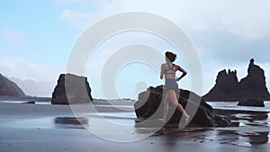 Barefoot sporty girl with slim body running along sea surf by water pool to keep fit and health. Beach background with