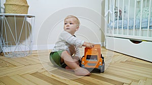 Barefoot toddler boy playing with toy car in bedroom
